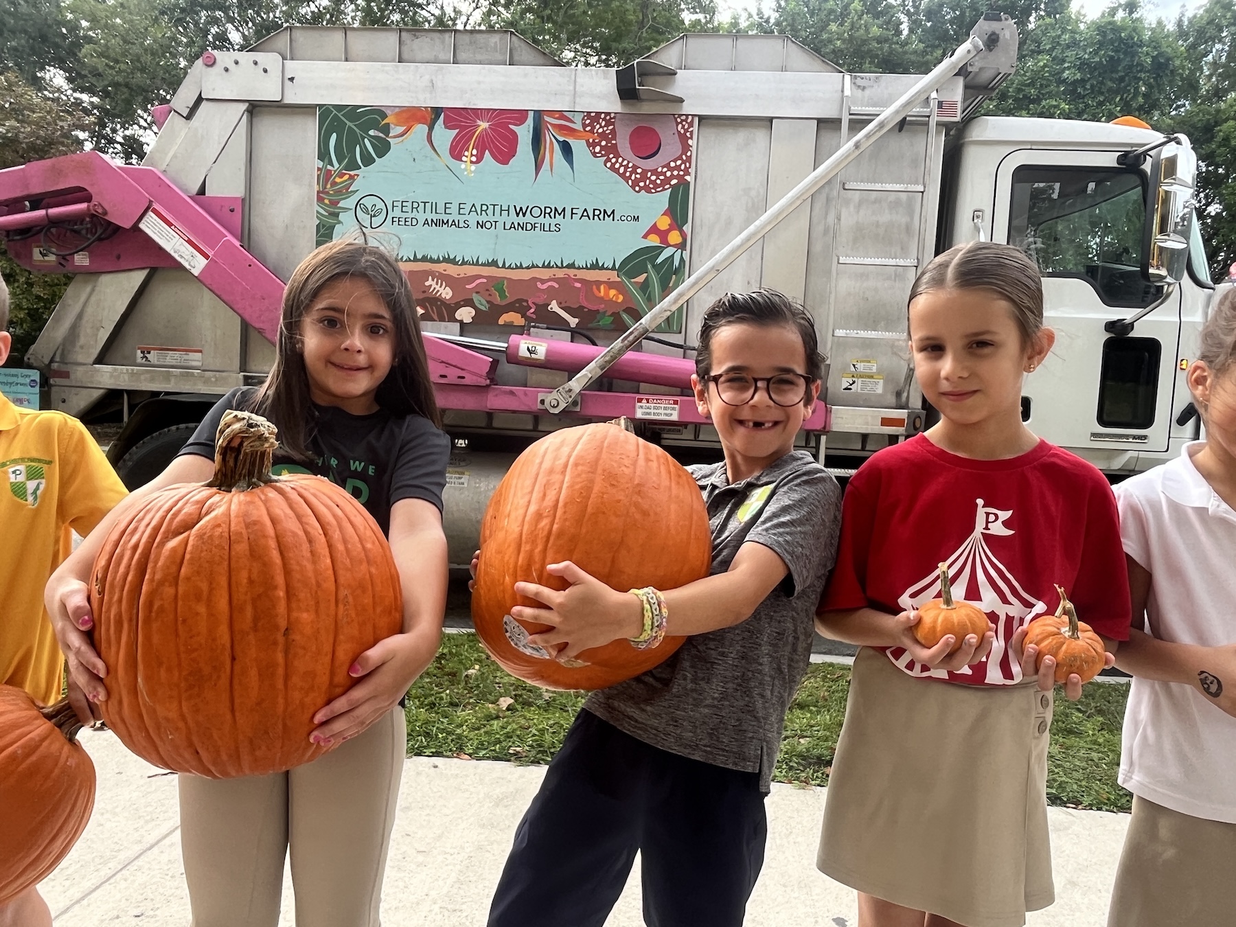 Students holding pumpkins in front of the Fertile Earth collection truck